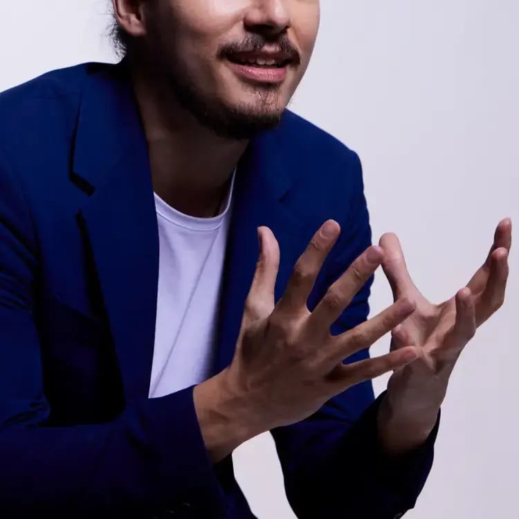 Photo of an Asian man wearing a blue sport coat and leaning forward excitedly