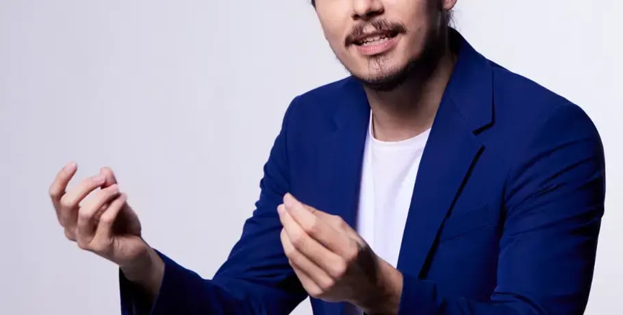 Photo of an Asian man in a blue sport coat gesturing with both hands