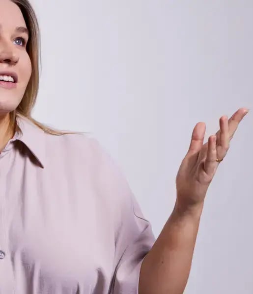 Photo of a blonde haired woman with a pick top gesturing with her hand