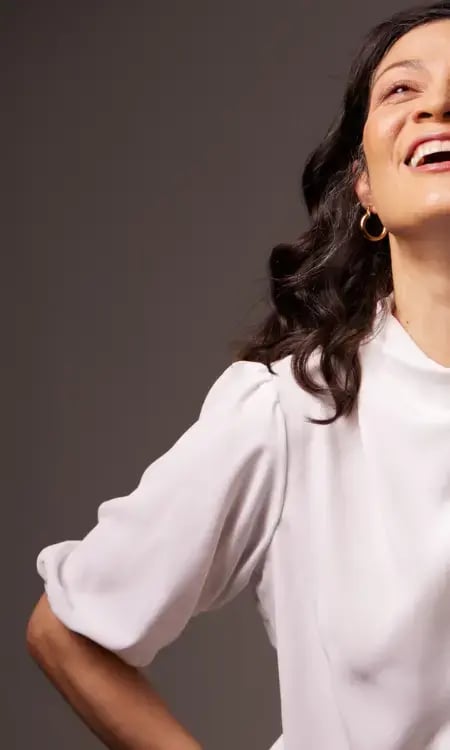 A photo of a woman with brown hair and a white top smiling